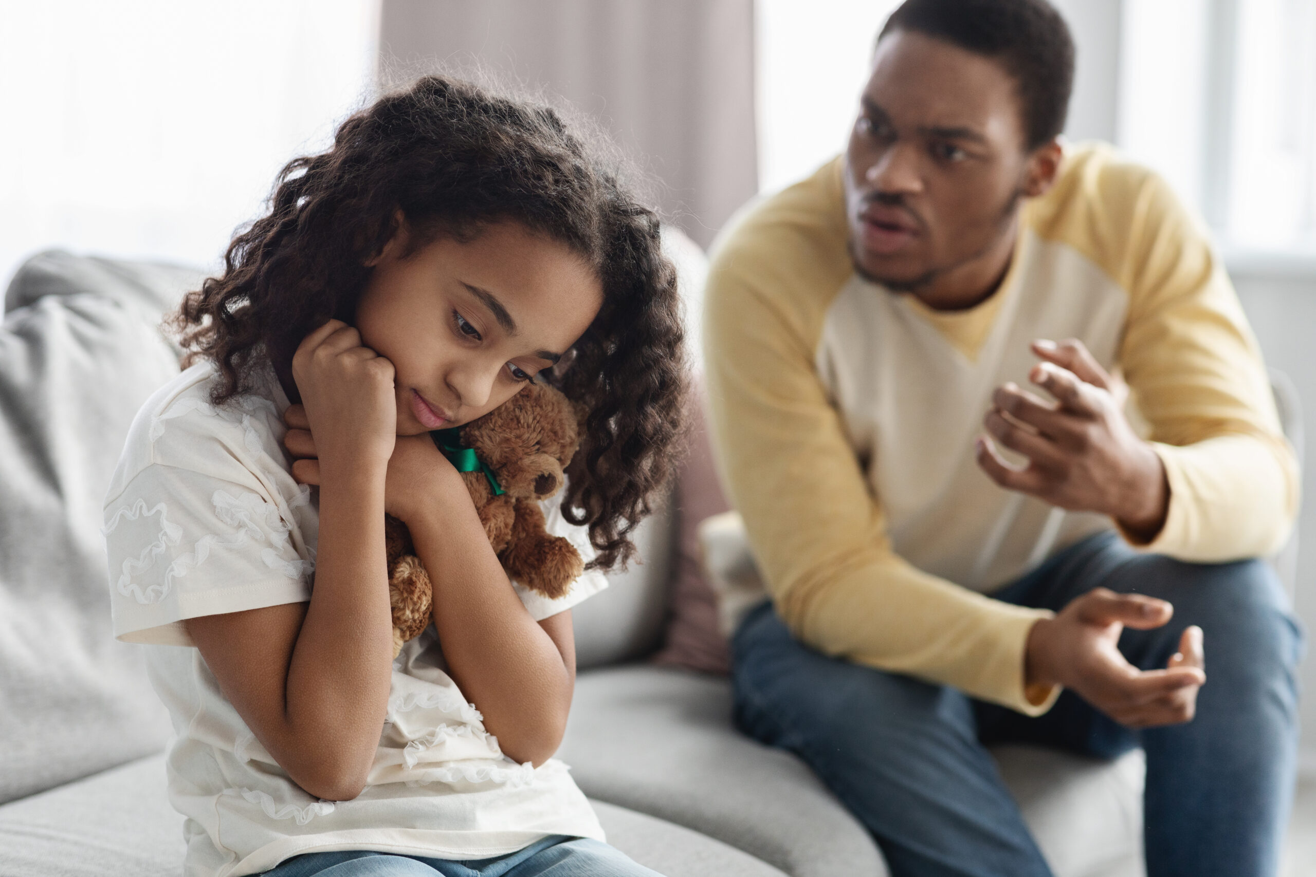 Father shouting at his daughter while she is holding a teddy bear