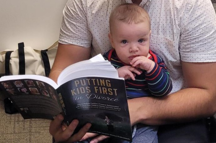 Father reading his son a book on putting kids first in divorce