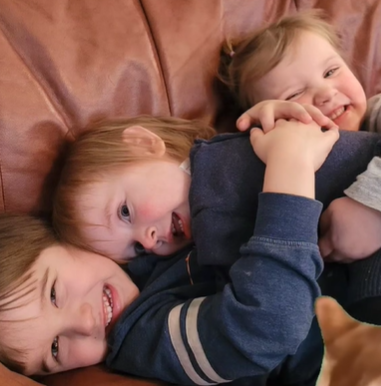 Three smiling siblings cuddling together on a couch, symbolizing the family bond and the importance of child support arrangements in Saskatoon.