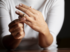 Close-up of a woman removing a wedding ring, symbolizing divorce and new beginnings. Learn about Collaborative Law and mediation options with family lawyers in Saskatoon.