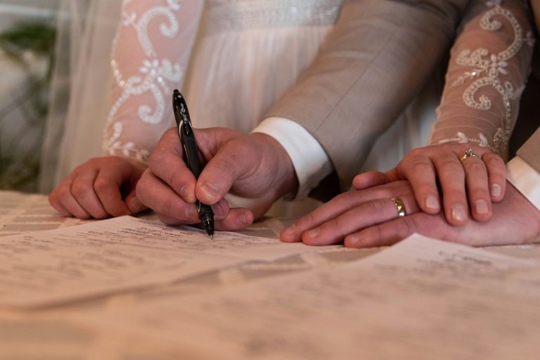 Couple signing marriage register while holding hands