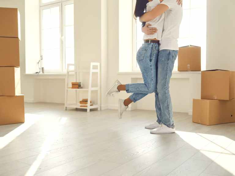 Engaged couple embracing after moving in to their first house