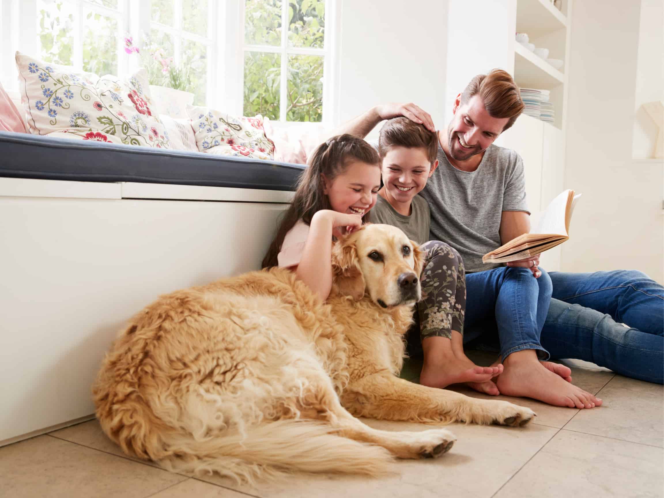 Father reading to his children while they pet the family dog