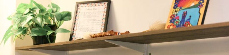 Shelf with an Indigenous talking stick on it
